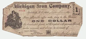 A worn, 19th-century one-dollar paper note issued by the Michigan Iron Company, featuring an illustration of a seated figure on the left and red serial number 6418.
