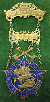 An ornate gold badge with top bars reading 'Past Grand President', connected by chains to a blue enamel star pendant depicting Saint George slaying a dragon.