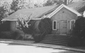 A brick building with front steps leading to wooden doors beneath a small Star of David.